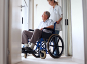 Photo of a man sitting in a wheelchair. House and car in the background.