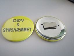 Gul badge med magnet. Tekst: Døv og Synshæmmet Gul badge med magnet. Tekst: Døv og Synshæmmet